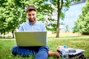 Man using a laptop while sitting on grass